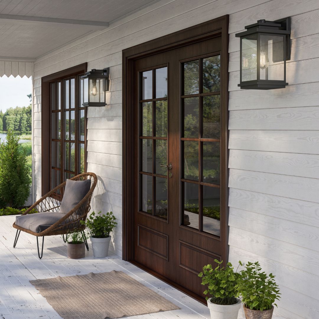 A white-paneled porch featuring a dark wood double door and two black, traditional-style rectangular lanterns with Edison bulbs.